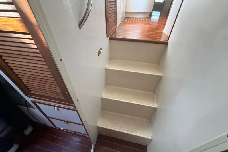 Slide: The Image of Interior stairs of a 1995 Manta Sailing Catamaran with wooden accents and white walls. - 52