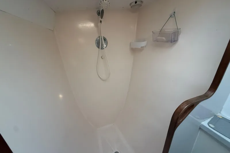 Slide: The Image of Shower area inside a 1995 Manta Sailing Catamaran, featuring a handheld showerhead and storage shelves. - 64