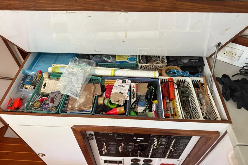 Slide: The Image of Storage compartment on 1995 Manta SAILING CATAMARAN filled with various tools and supplies. - 69