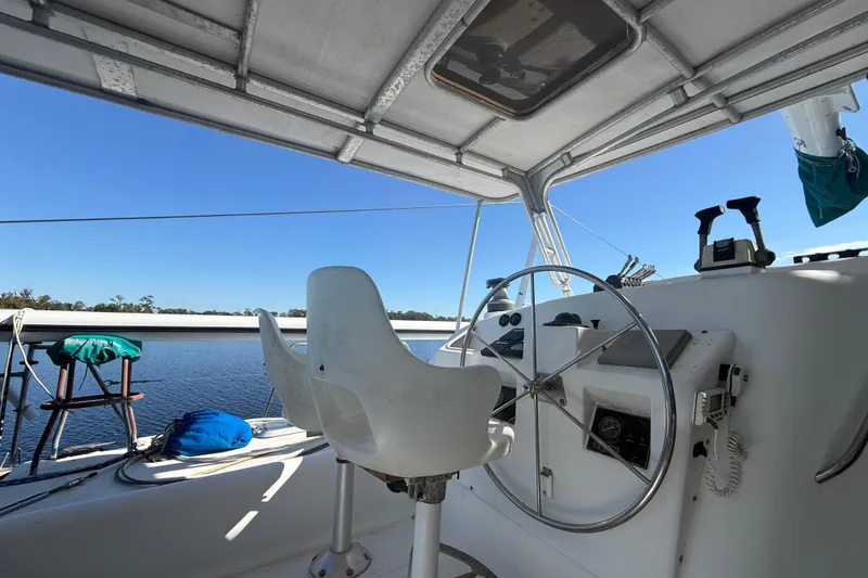 Slide: The Image of Cockpit of 1995 Manta Sailing Catamaran with steering wheel and seating, overlooking calm waters. - 9