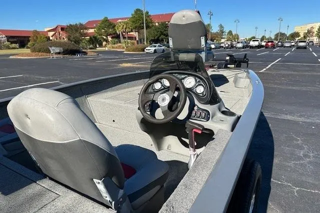 Slide: The Image of 2016 Bass Tracker 175 TF boat interior with steering wheel and seats in a parking lot. - 5