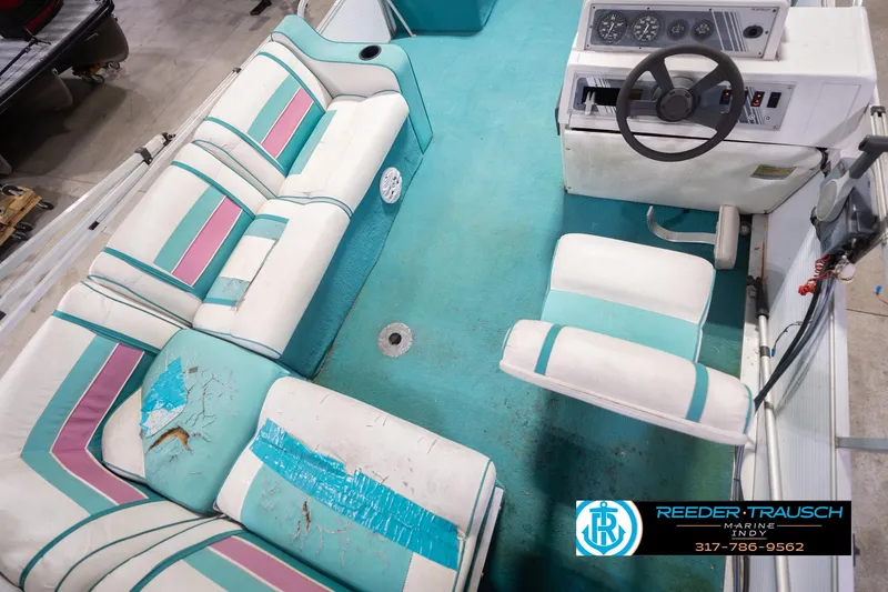 Slide: The Image of 1993 Avalon Playbouy Challenger boat interior with worn teal and pink seating, steering console visible. - 13
