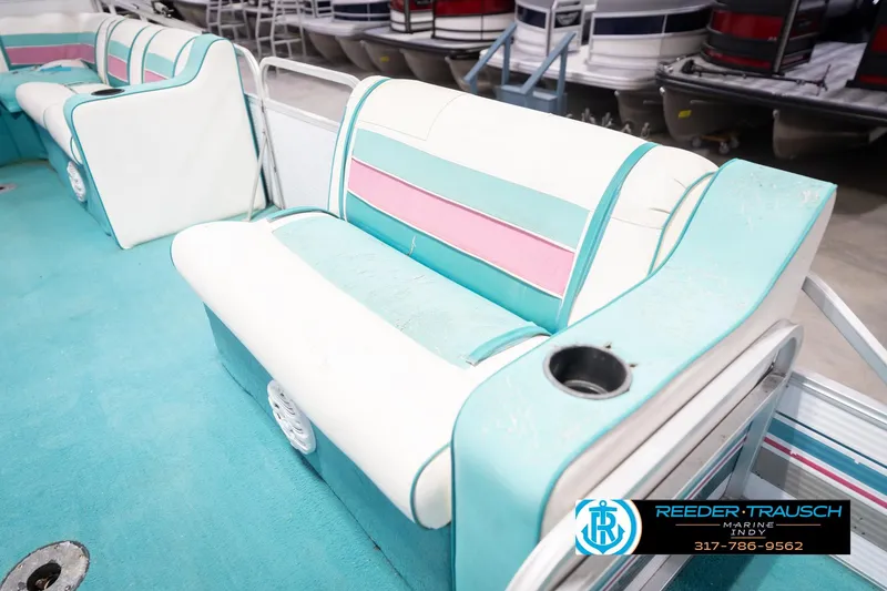 Slide: The Image of 1993 Avalon Playbouy Challenger boat interior with teal and pink seating, cup holder, and speakers. - 21