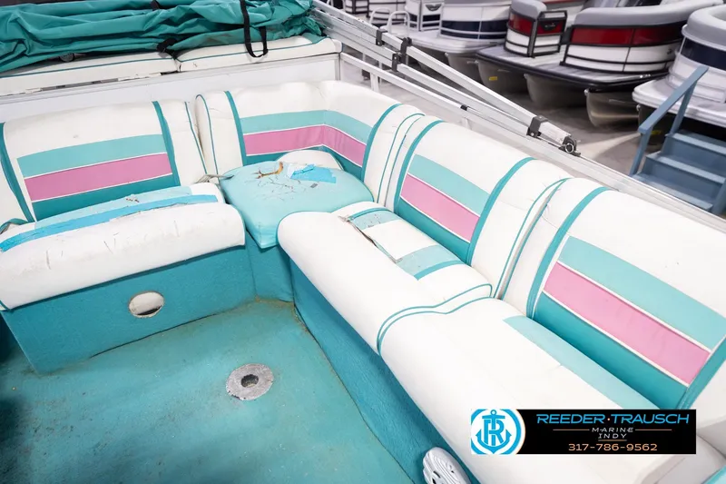 Slide: The Image of 1993 Avalon Playbouy Challenger boat interior with teal and pink seating, showing wear and tear. - 35