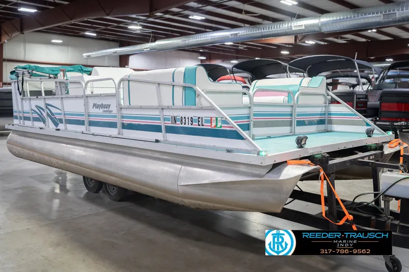 Slide: The Image of 1993 Avalon Playbouy Challenger pontoon boat in indoor showroom, featuring teal and white design. - 5