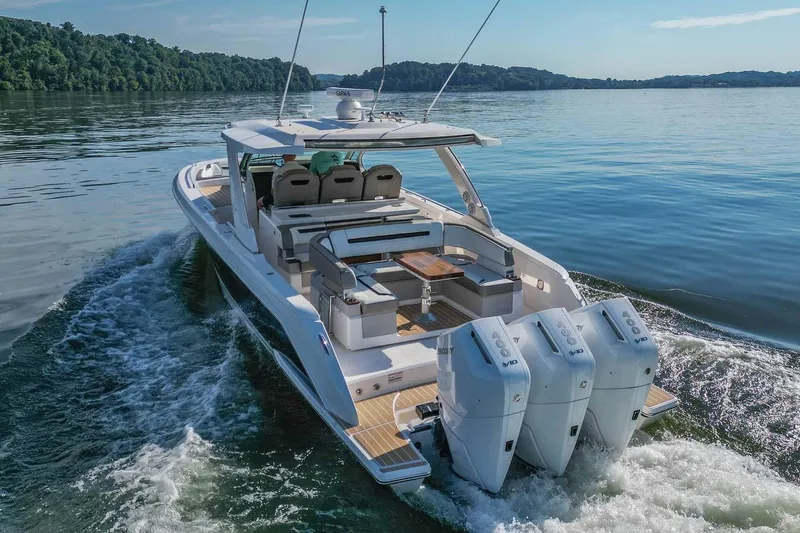 Slide: The Image of 2024 Tiara Yachts 38 LS cruising on a serene lake with triple outboard engines. - 14