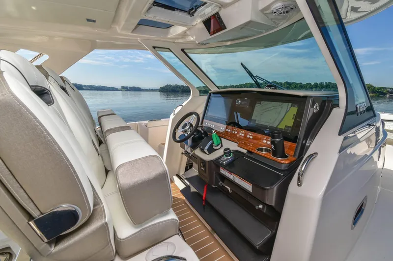 Slide: The Image of 2024 Tiara Yachts 38 LS helm with modern controls and luxurious seating on calm waters. - 21