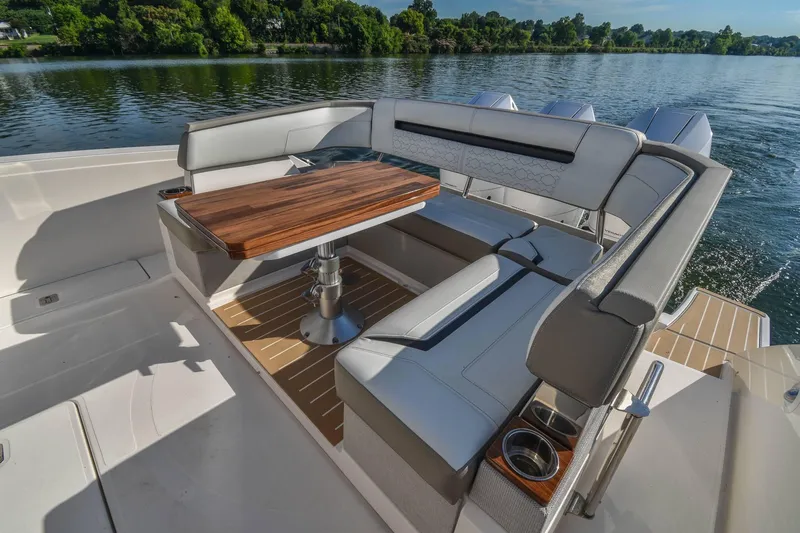 Slide: The Image of 2024 Tiara Yachts 38 LS luxury seating area with wooden table on a serene lake. - 24
