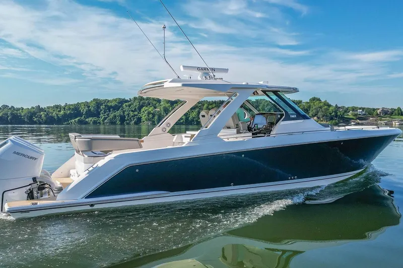 Slide: The Image of 2024 Tiara Yachts 38 LS cruising on a serene lake under a clear blue sky. - 3