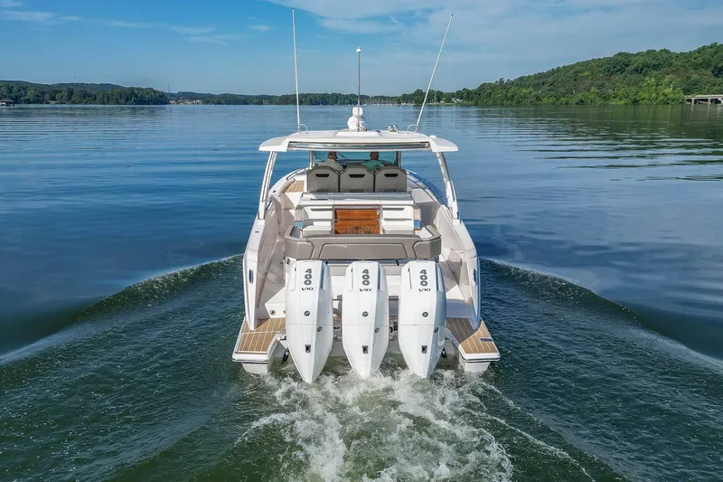 Slide: The Image of 2024 Tiara Yachts 38 LS cruising on a serene lake with triple outboard engines. - 5