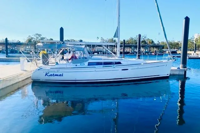 Slide: The Image of 2013 Beneteau Oceanis 37 sailboat docked in a marina, reflecting on calm water. - 2