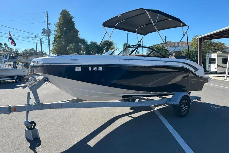 Slide: The Image of 2020 Bayliner DX 2000 boat on trailer, parked outdoors under clear blue sky. - 5