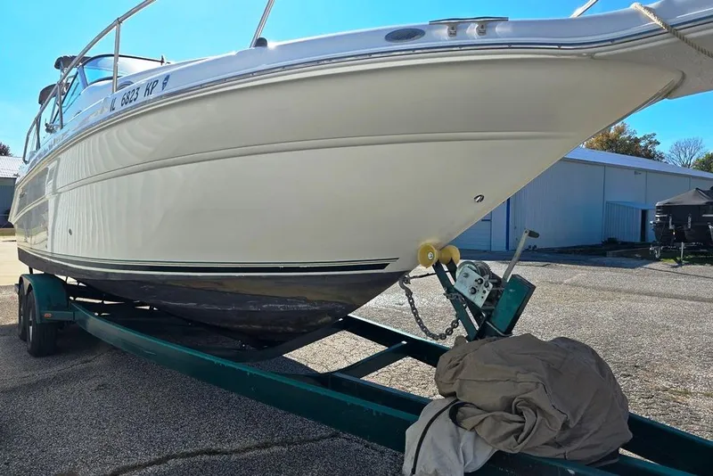 Slide: The Image of 1999 Sea Ray 270 Sundancer boat with canopy, on trailer, docked outdoors. - 14