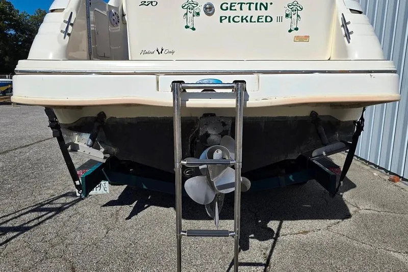 Slide: The Image of 1999 Sea Ray 270 Sundancer boat interior with white seating and table on teak deck. - 17