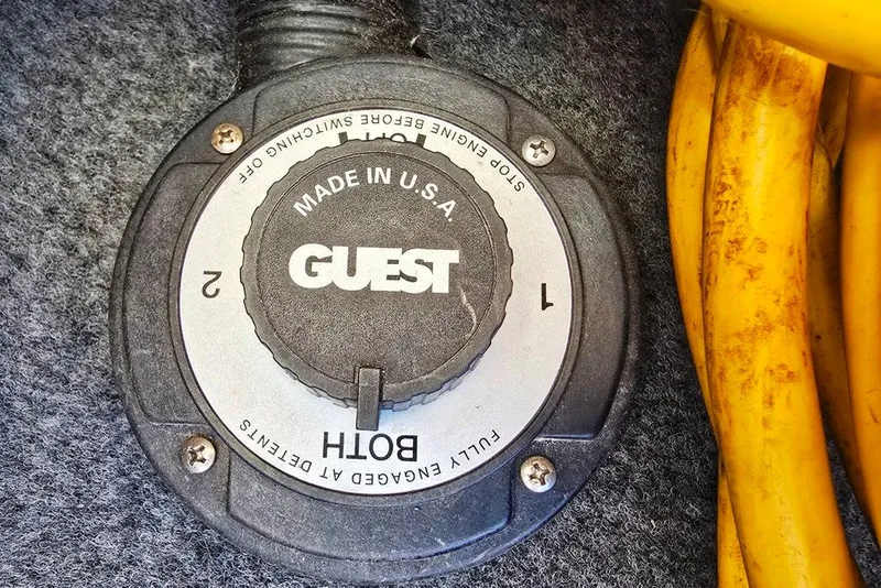 Slide: The Image of Battery switch on 1999 Sea Ray 270 Sundancer boat, labeled "Guest," with yellow cables. - 27