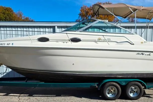 Slide: The Image of 1999 Sea Ray 270 Sundancer boat on trailer, parked outdoors with blue sky background. - 28