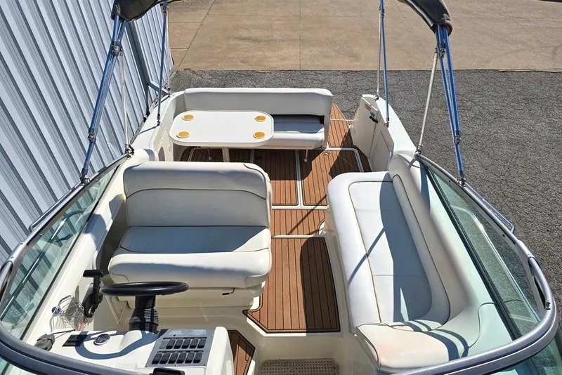 Slide: The Image of 1999 Sea Ray 270 Sundancer boat interior with white seating and wooden flooring. - 3