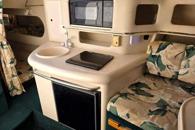 Slide: The Image of Interior of a 1999 Sea Ray 270 Sundancer with floral seating and a central table. - 7
