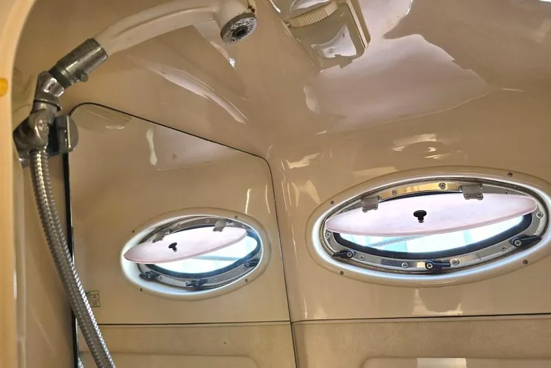 Slide: The Image of 1999 Sea Ray 270 Sundancer bathroom with sink, toilet, and porthole window. - 9