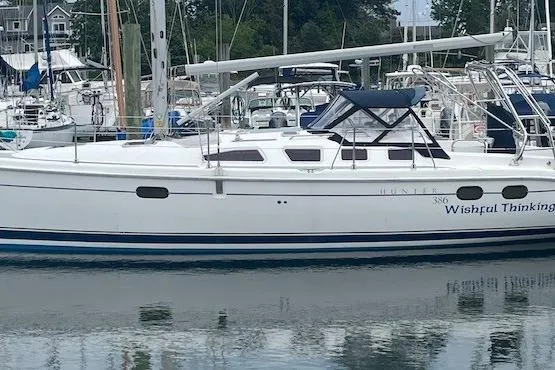 Slide: The Image of 2004 Hunter 386 sailboat docked in marina, featuring sleek white design and blue accents. - 1