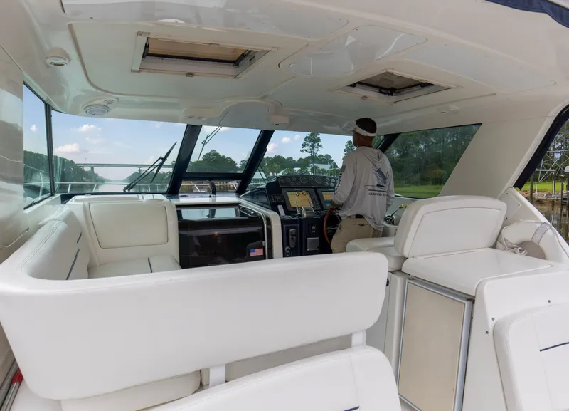 Slide: The Image of 2005 Tiara Yachts 3600 Sovran interior with captain at helm, featuring white seating and navigation equipment. - 19