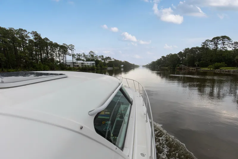 Slide: The Image of 2005 Tiara Yachts 3600 Sovran cruising on a serene river with lush tree-lined banks. - 29