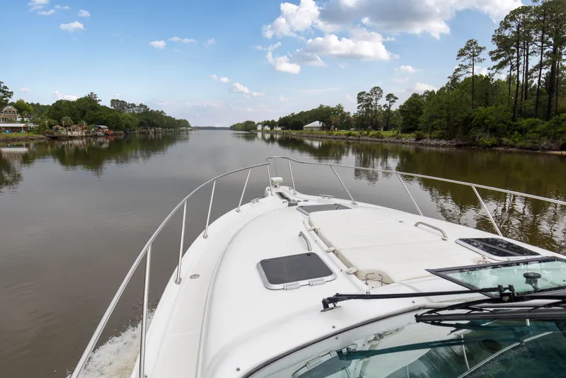 Slide: The Image of 2005 Tiara Yachts 3600 Sovran cruising on a serene river with lush greenery. - 32