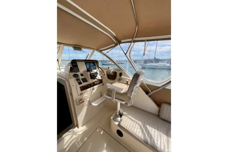 Slide: The Image of 2005 Mainship Pilot 30-II helm with steering wheel, controls, and marina view. - 15