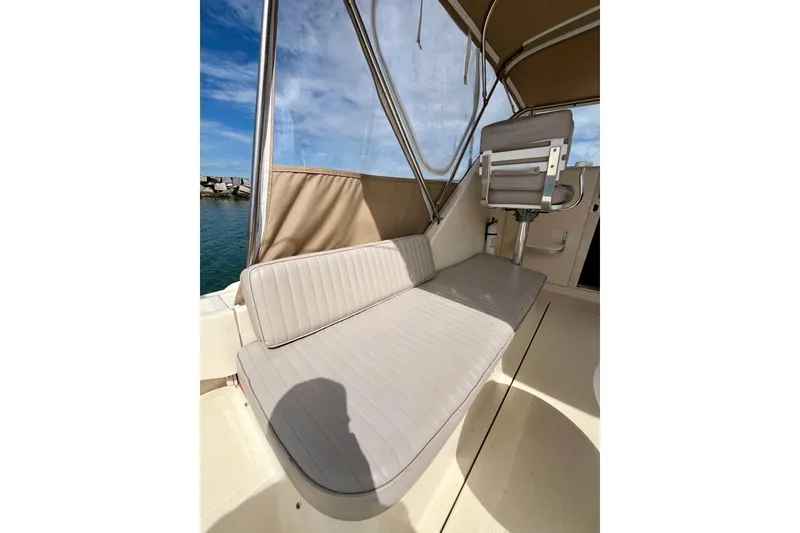 Slide: The Image of 2005 Mainship Pilot 30-II boat interior with beige seating and helm chair under canopy. - 17