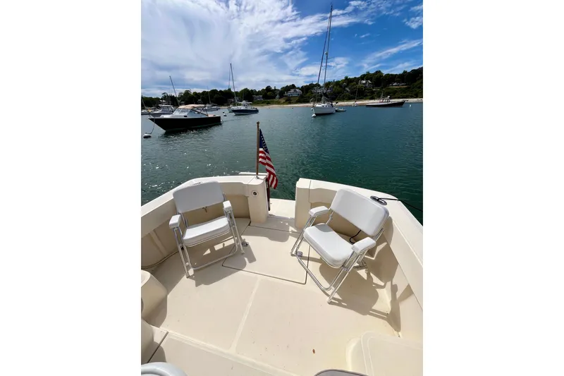 Slide: The Image of 2005 Mainship Pilot 30-II boat deck with chairs, American flag, and scenic harbor view. - 19