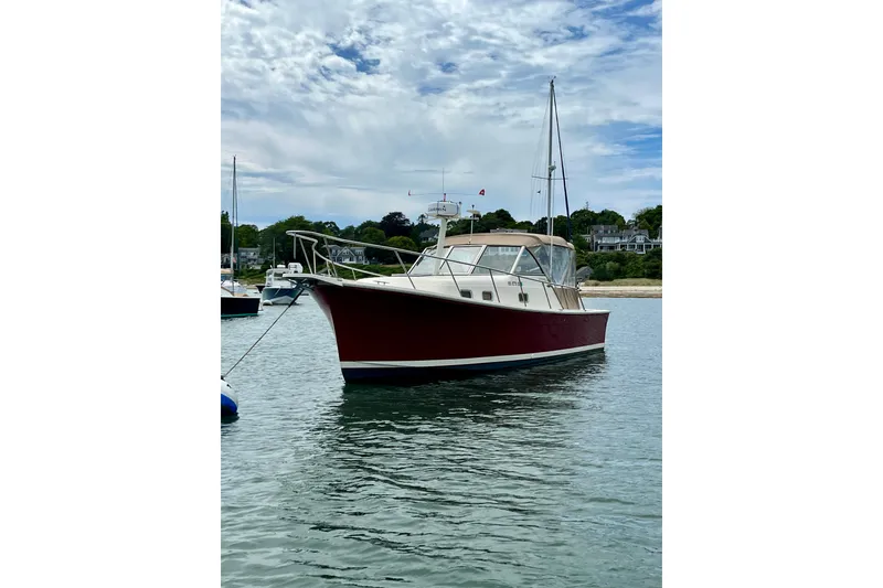 Slide: The Image of 2005 Mainship Pilot 30-II boat anchored in calm waters under a cloudy sky. - 2