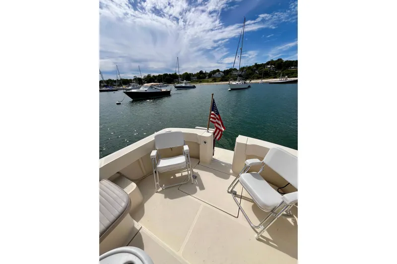 Slide: The Image of 2005 Mainship Pilot 30-II boat deck with chairs, American flag, and scenic harbor view. - 20
