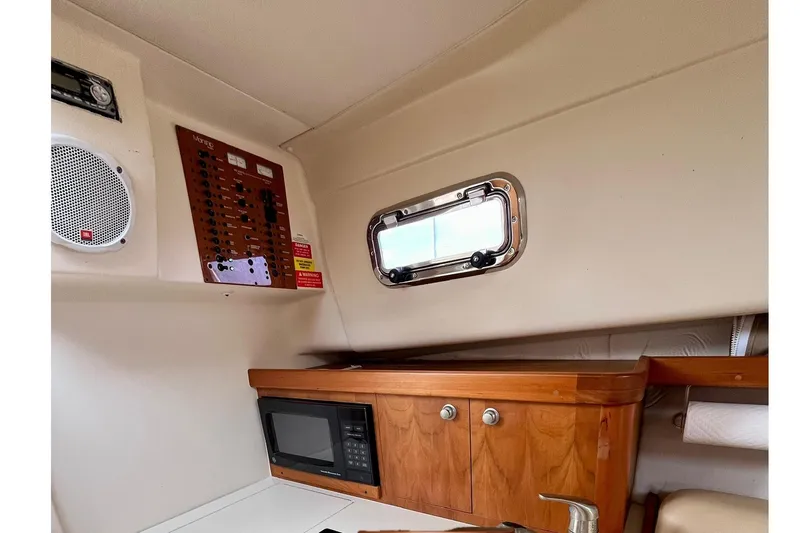 Slide: The Image of 2005 Mainship Pilot 30-II cabin interior with microwave, control panel, and porthole window. - 32