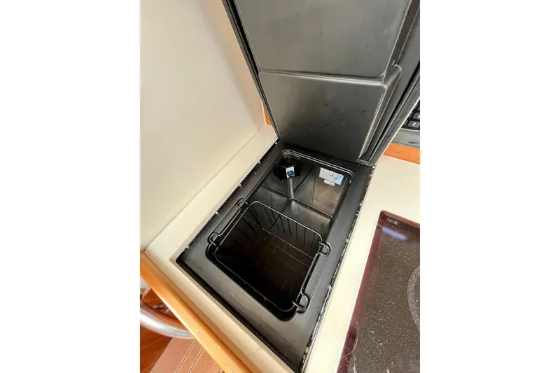 Slide: The Image of Open storage compartment on 2005 Mainship Pilot 30-II boat, featuring a black interior. - 34