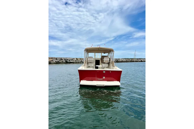Slide: The Image of 2005 Mainship Pilot 30-II boat on water, red hull, clear sky background. - 6