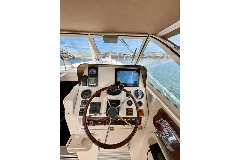 Slide: The Image of 2005 Mainship Pilot 30-II helm with navigation instruments and steering wheel, overlooking marina. - 9