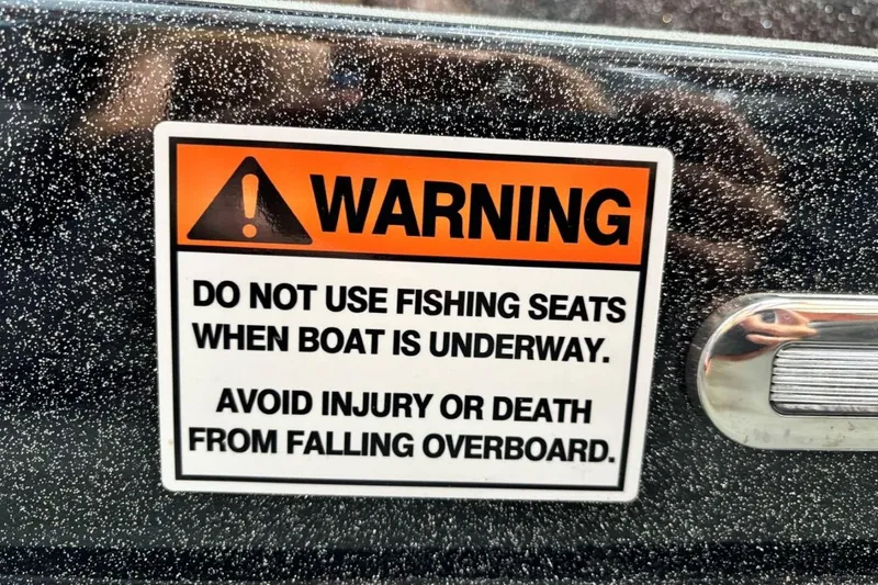 Slide: The Image of Warning label on 2025 Falcon Boats 21 Predator, cautioning against using fishing seats underway. - 27