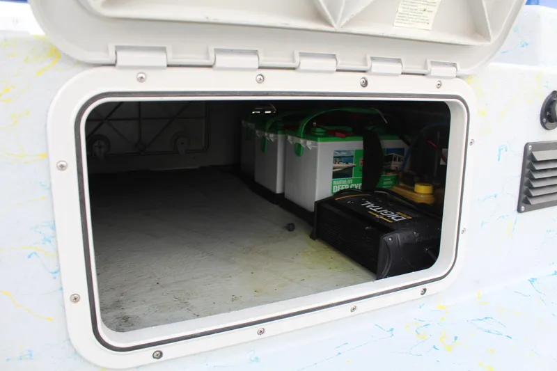Slide: The Image of Open storage compartment in a 2015 Shoalwater 23 Catamaran, showing batteries and equipment. - 16
