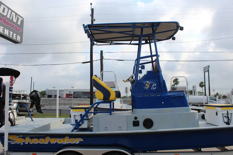 Slide: The Image of 2015 Shoalwater 23 Catamaran with blue and yellow accents, parked on a trailer. - 17