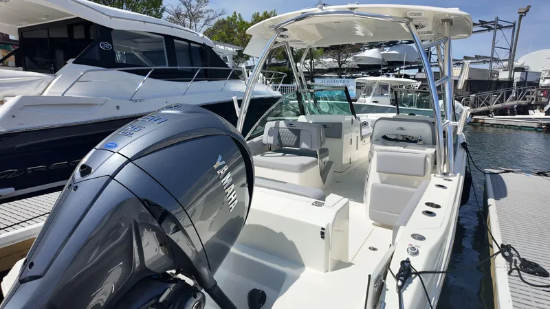 Slide: The Image of 2025 Cobia 240 Dual Console boat with Yamaha engine docked in a marina. - 2