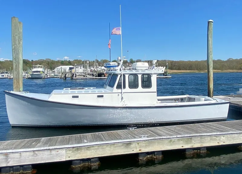 The Image of 1990 South Shore 30 Downeast boat docked at a marina under clear blue skies. - 0