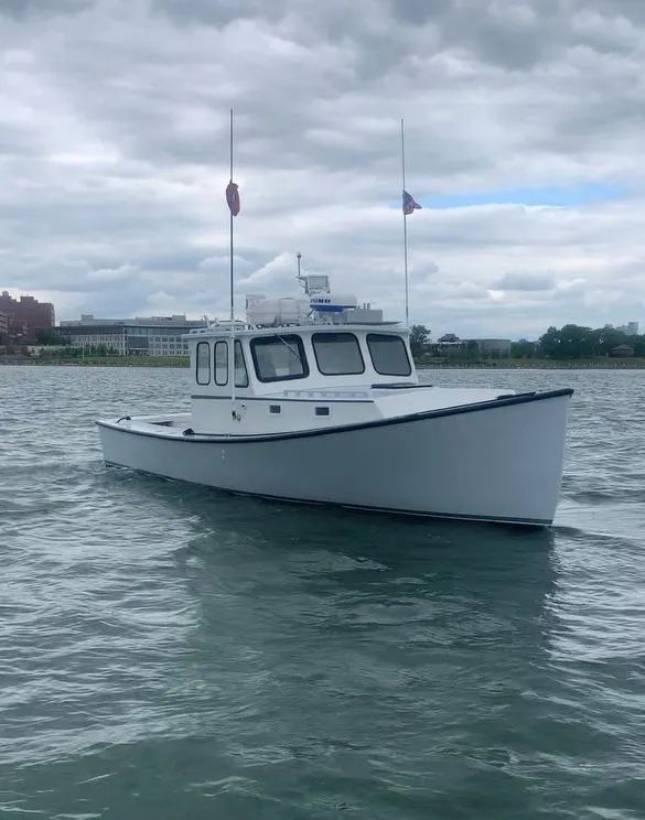 Slide: The Image of 1990 South Shore 30 Downeast boat on calm water under cloudy sky. - 2