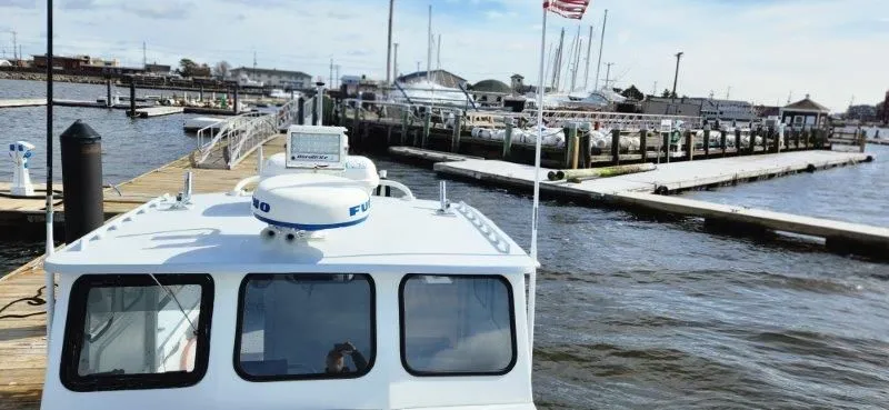 Slide: The Image of 1990 South Shore 30 Downeast boat docked at a marina with American flag. - 8