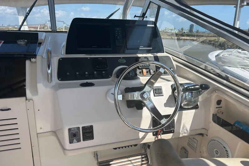 Slide: The Image of 2004 Grady-White Marlin 300 boat helm with steering wheel and navigation equipment. - 11