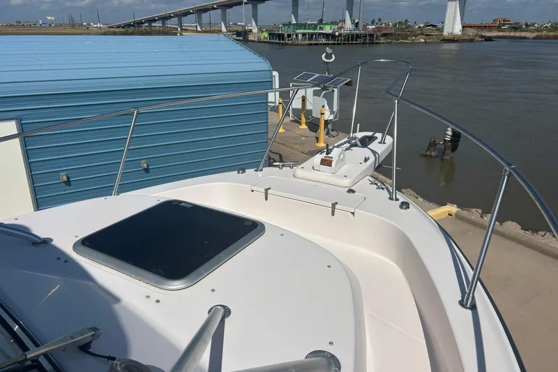 Slide: The Image of 2004 Grady-White Marlin 300 boat docked near a blue building and bridge. - 29