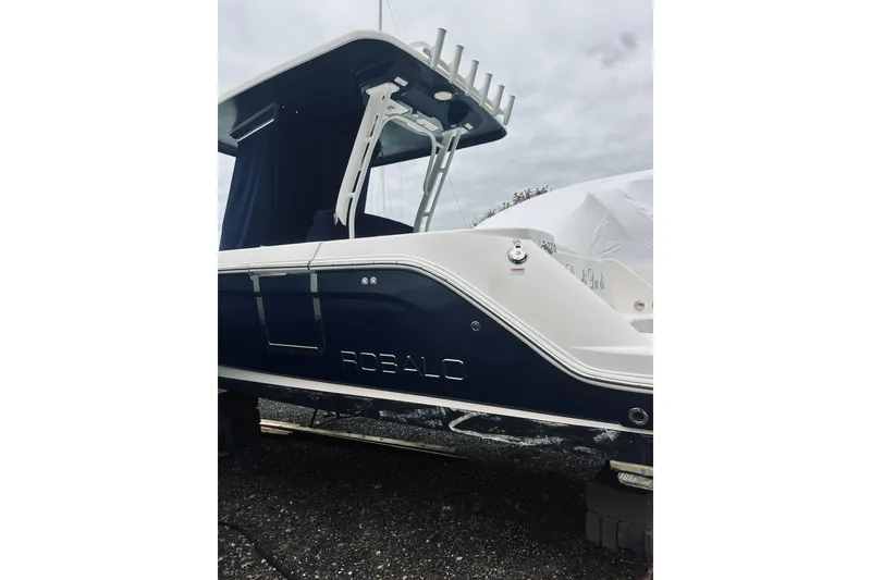 Slide: The Image of 2022 Robalo R272 Center Console boat, side view, dark blue and white design. - 23