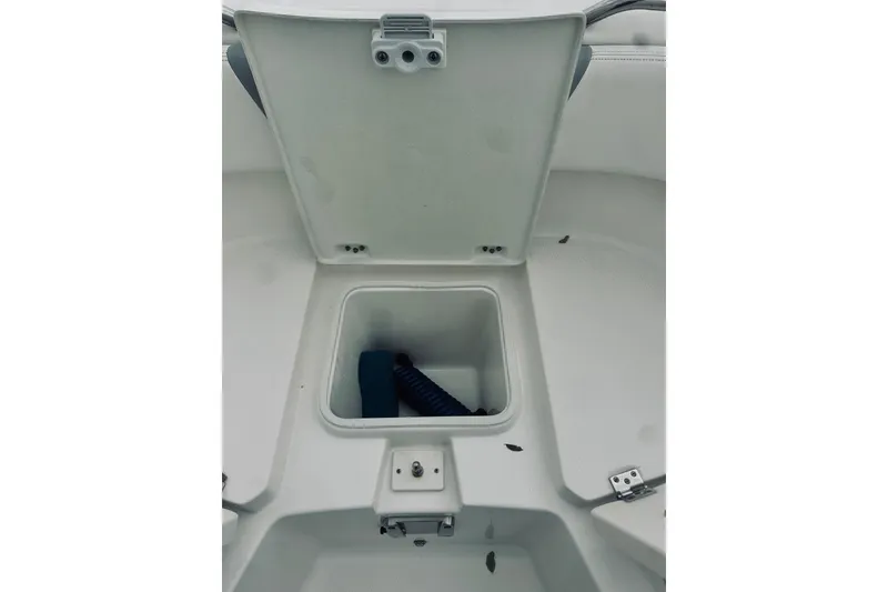 Slide: The Image of 2022 Robalo R272 Center Console storage compartment with open lid and coiled rope inside. - 78