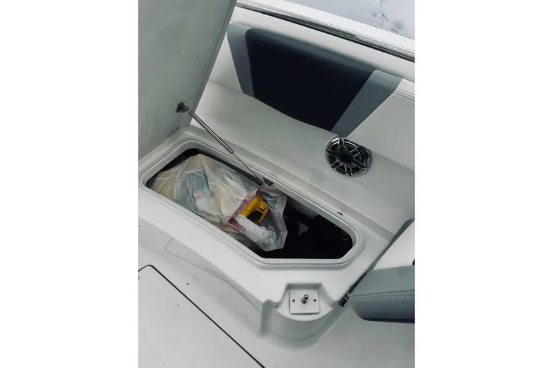 Slide: The Image of Open storage compartment on 2022 Robalo R272 Center Console boat, showing interior contents. - 79