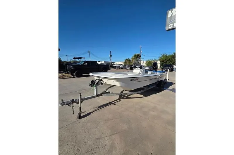 Slide: The Image of 2018 Mako Pro Skiff 17 CC boat on trailer, parked outdoors under clear blue sky. - 1