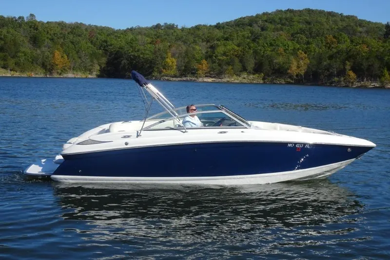 The Image of 2008 Cobalt 232 boat cruising on a scenic lake with forested hills in the background. - 0
